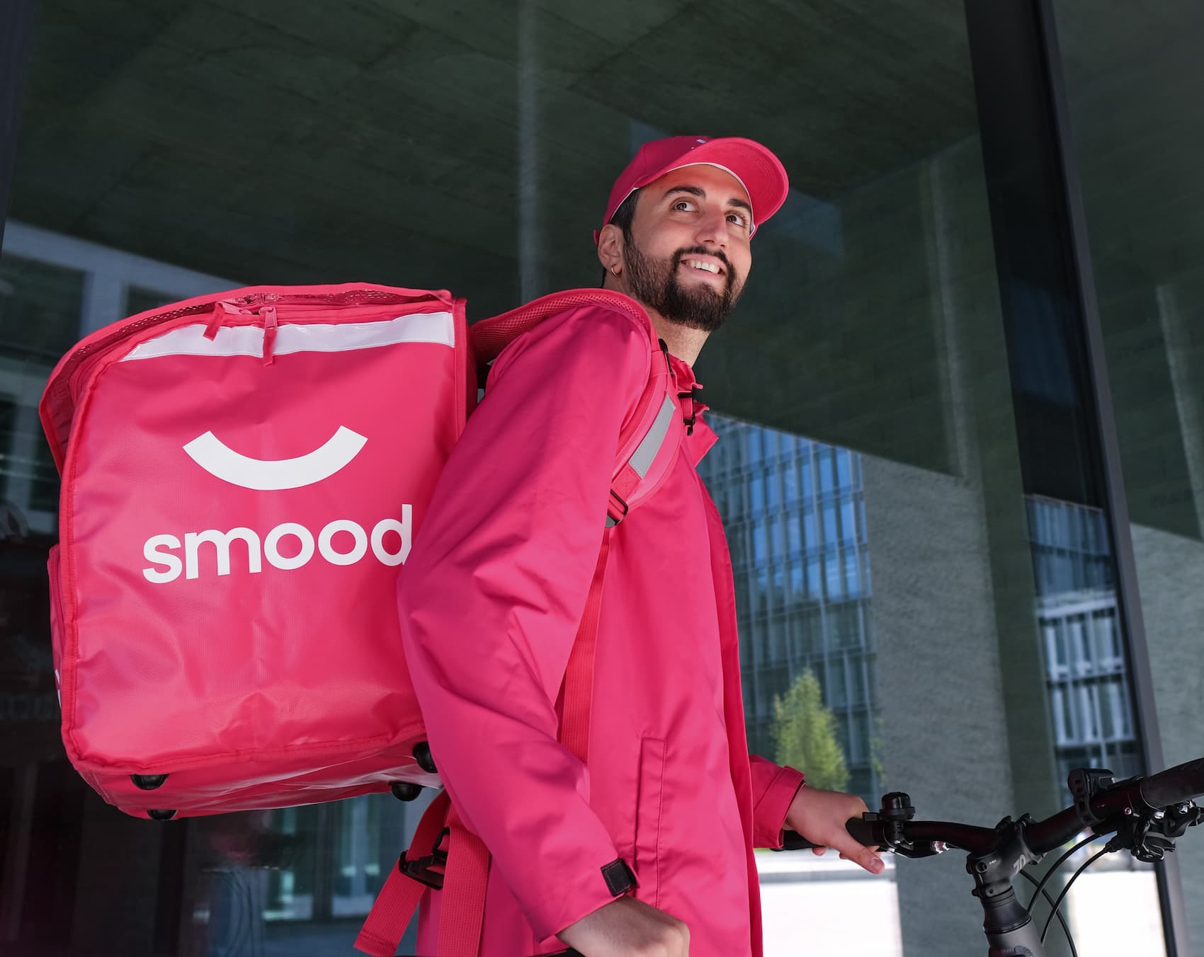 Smiling delivery rider carrying a Smood bag, ready to deliver groceries.